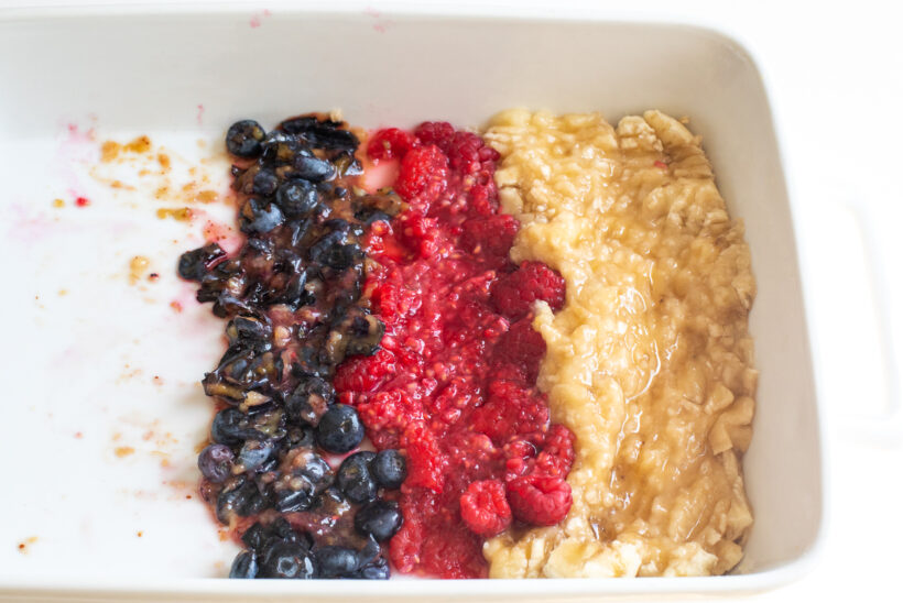 Berries and banana mashed in a white baking dish.