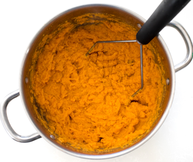 mashed sweet potatoes in large pot with masher