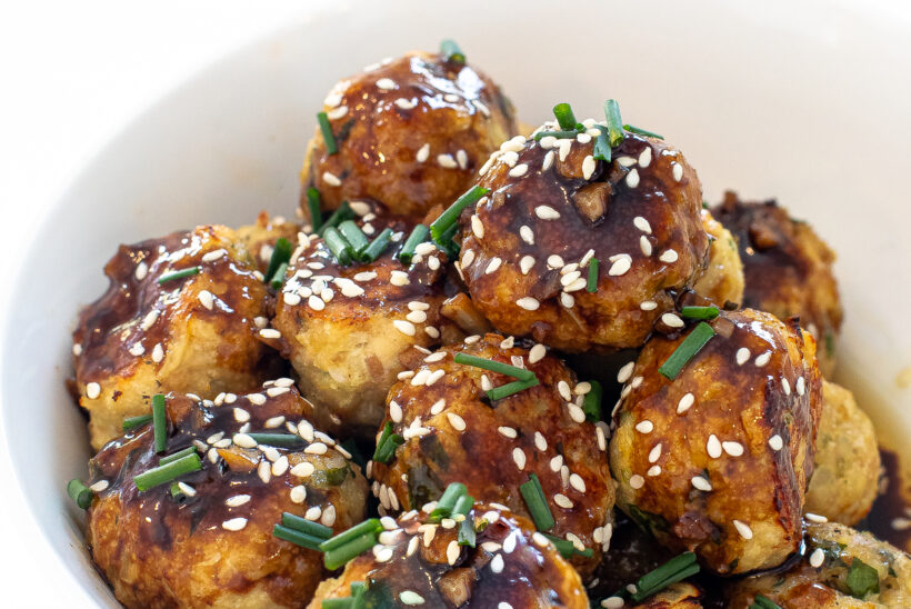 chicken meatballs tossed in asian sauce in a white bowl