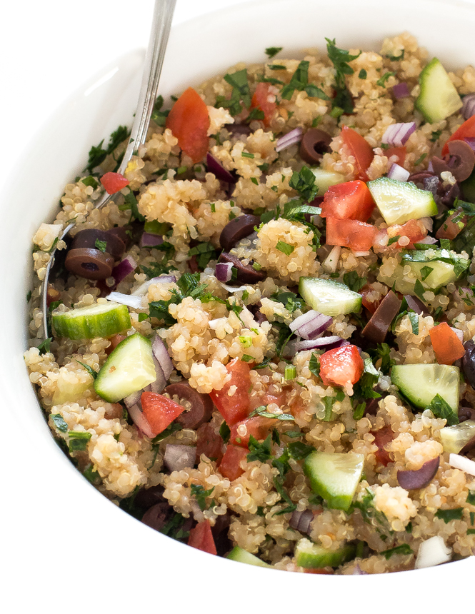 Close up of Mediterranean quinoa with a spoon in a white bowl.