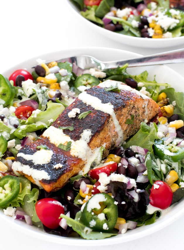 Mexican salmon salad assembled in a white bowl and topped with dressing.