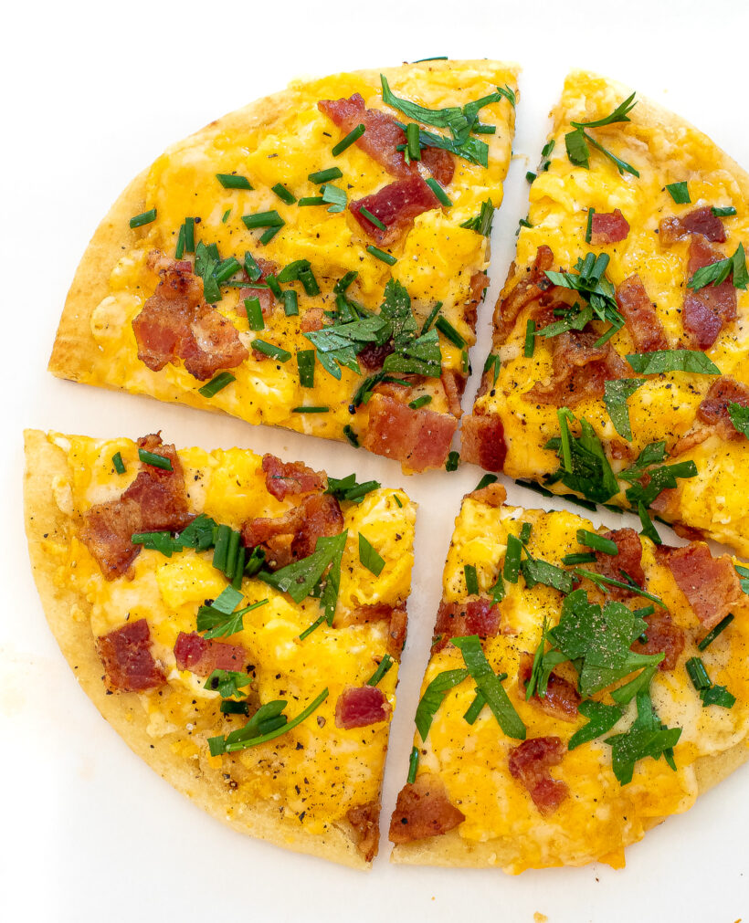 Overhead view of breakfast pizza cut into four pieces. 