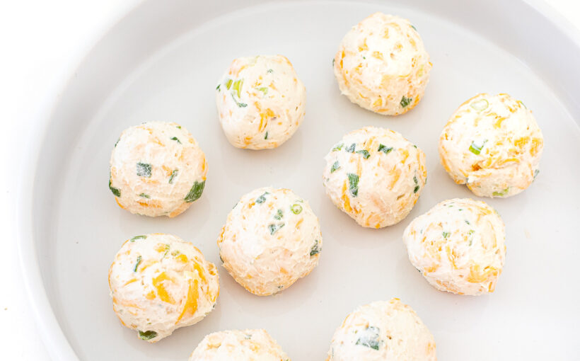 Cheese balls placed on a white plate before toppings are added.