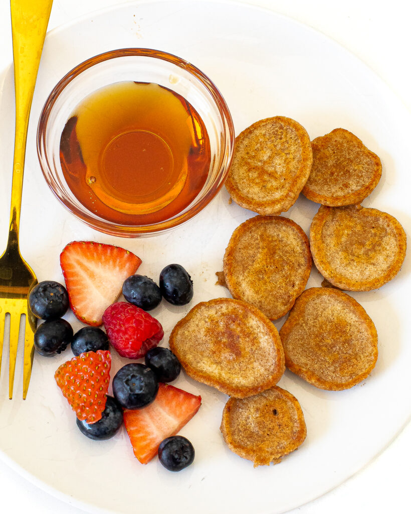 overhead shot of mini pancakes with fruit and maple syrup for dipping