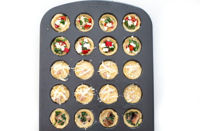 Mini quiches in a mini muffin tin before being baked.
