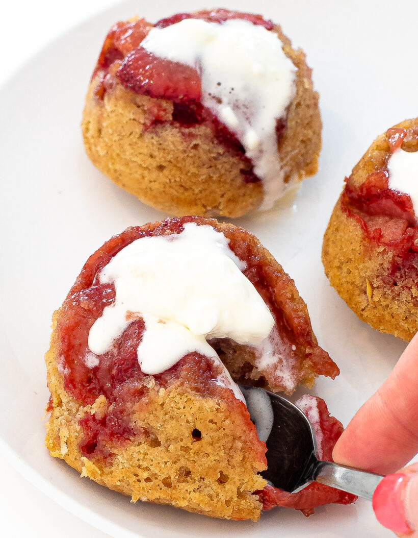 Hand holding a spoon taking a bite from a cake with ice cream on it. 