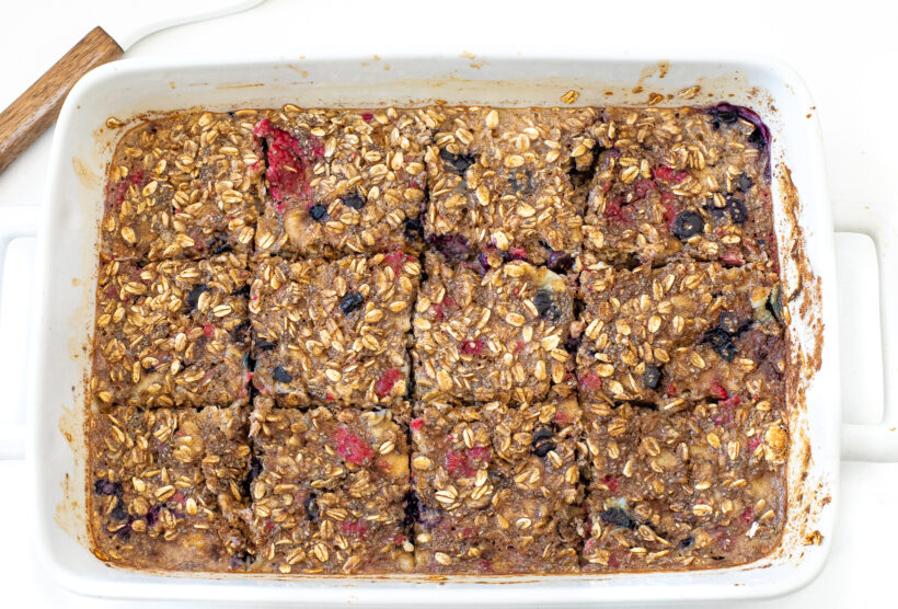 Baked oatmeal with berries in a baking dish cut into squares.