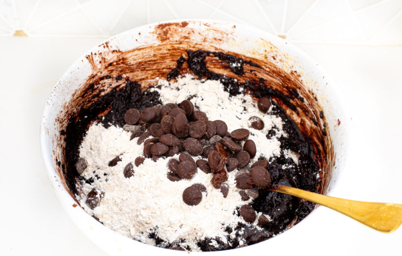 adding flour and chocolate chips to brownie batter