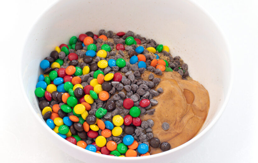 Ingredients for monster energy balls in a white mixing bowl.