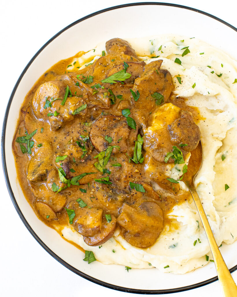 A plate of mashed potatoes topped with mushroom gravy.