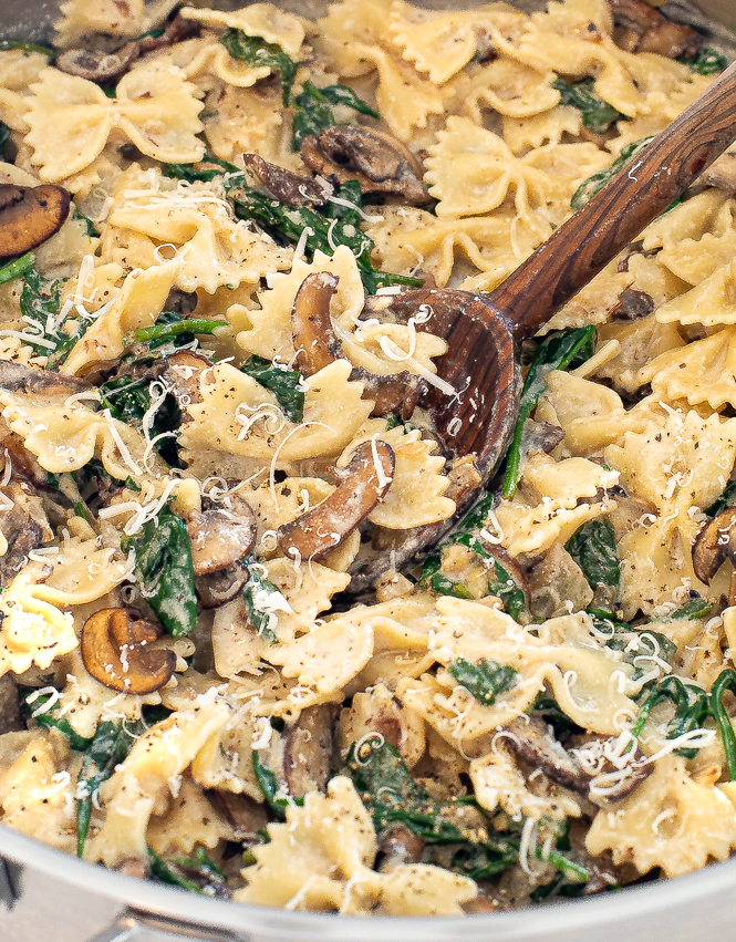 Up close shot of pasta being stirred by a wooden spoon.