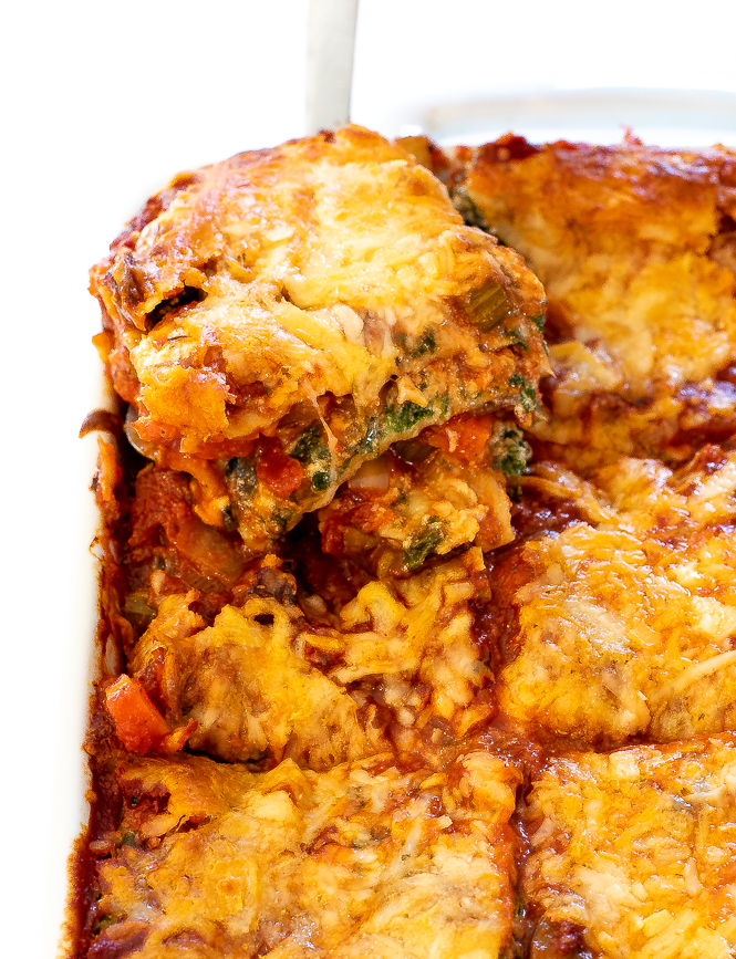 A slice of vegetarian lasagna being lifted from the casserole dish.