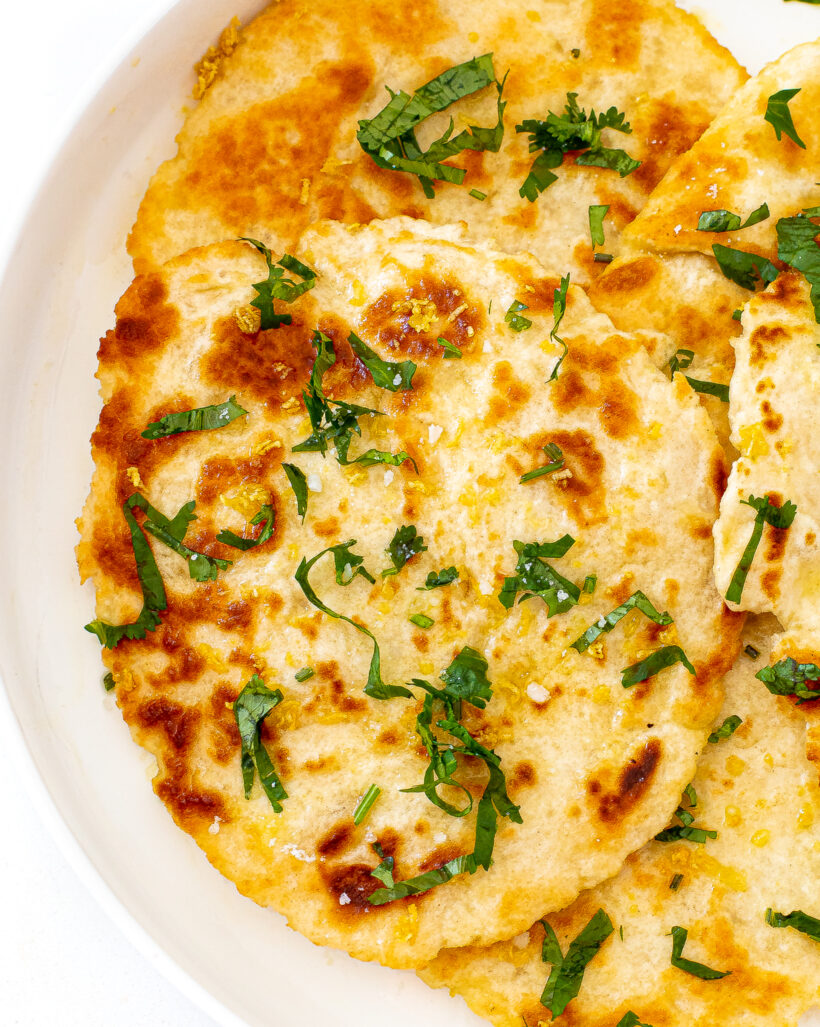 A top down view of pieces of naan bread on a white serving plate.