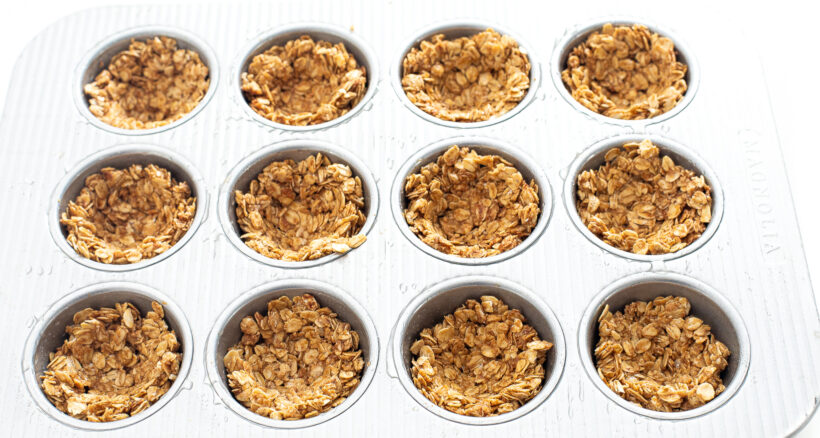Granola cups in a muffin tin before being baked.