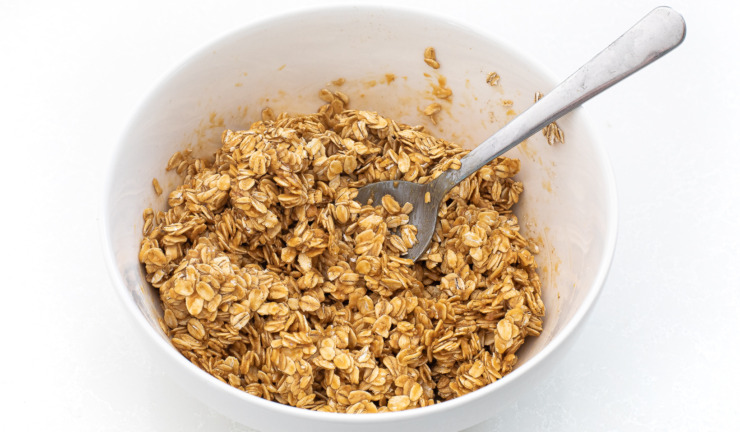 Oat mixture mixed up in a white bowl with a spoon.