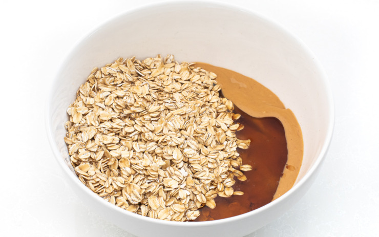 Oats, honey and peanut butter in a white bowl.