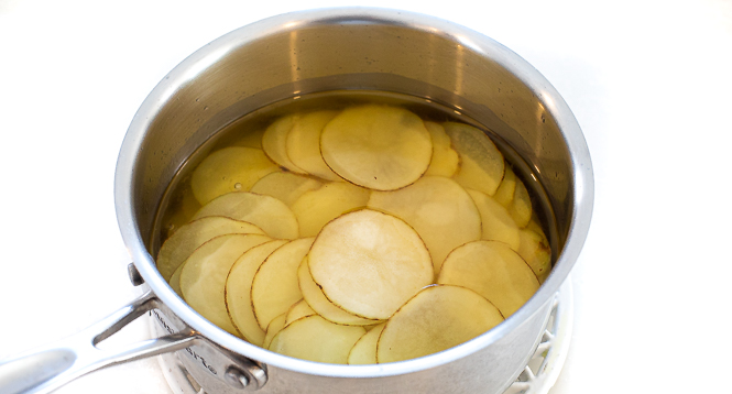 Oil and sliced potatoes in a sauce pan.