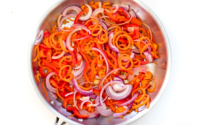 sautéing carrot spirals and red onion slices in large skillet