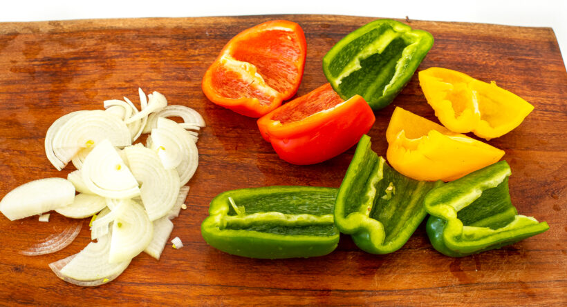 Onions and peppers on a cutting board.
