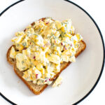 Overhead shot of a pieces of toast on a plate piled high with egg salad.