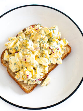 Overhead shot of a pieces of toast on a plate piled high with egg salad.