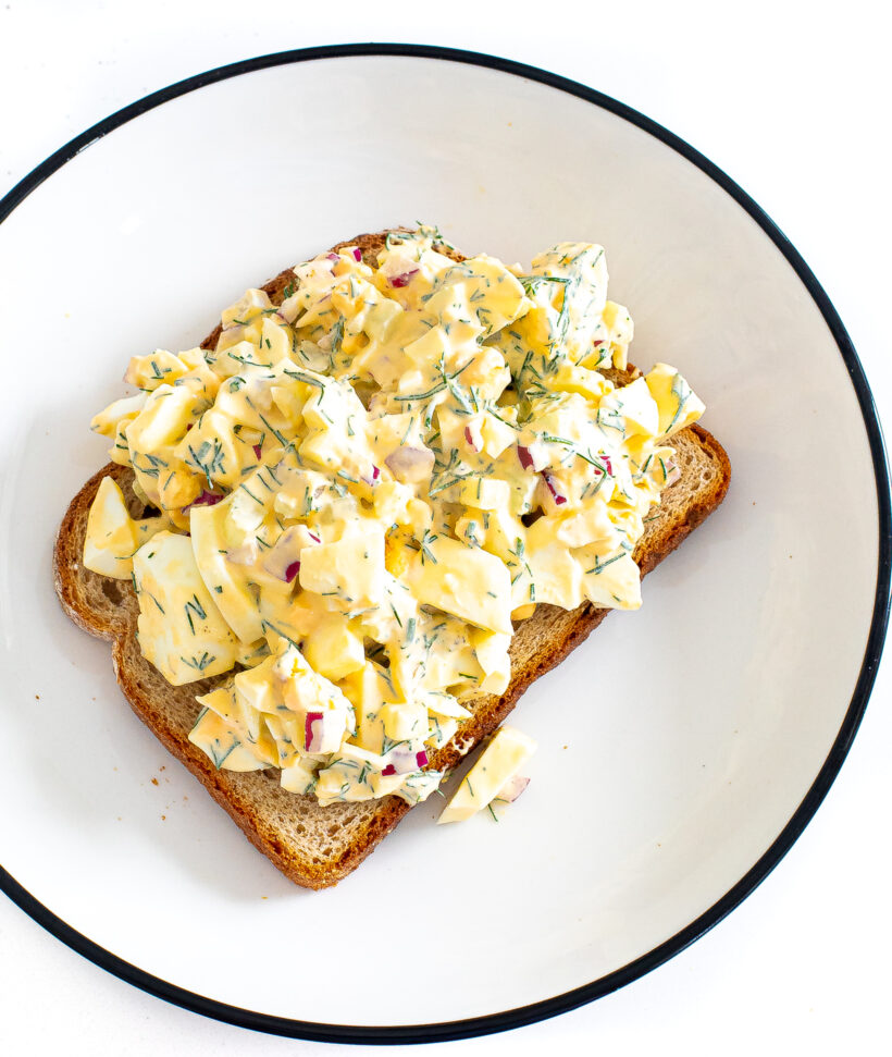 Overhead shot of a pieces of toast on a plate piled high with egg salad. 