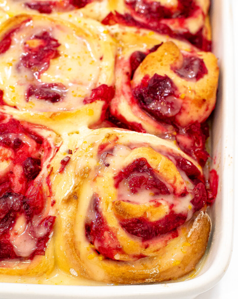 Corner view of cranberry orange rolls in a white baking dish after being baked.