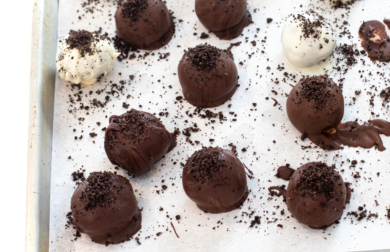sprinkling crushed up Oreo crumbs onto chocolate covered truffles
