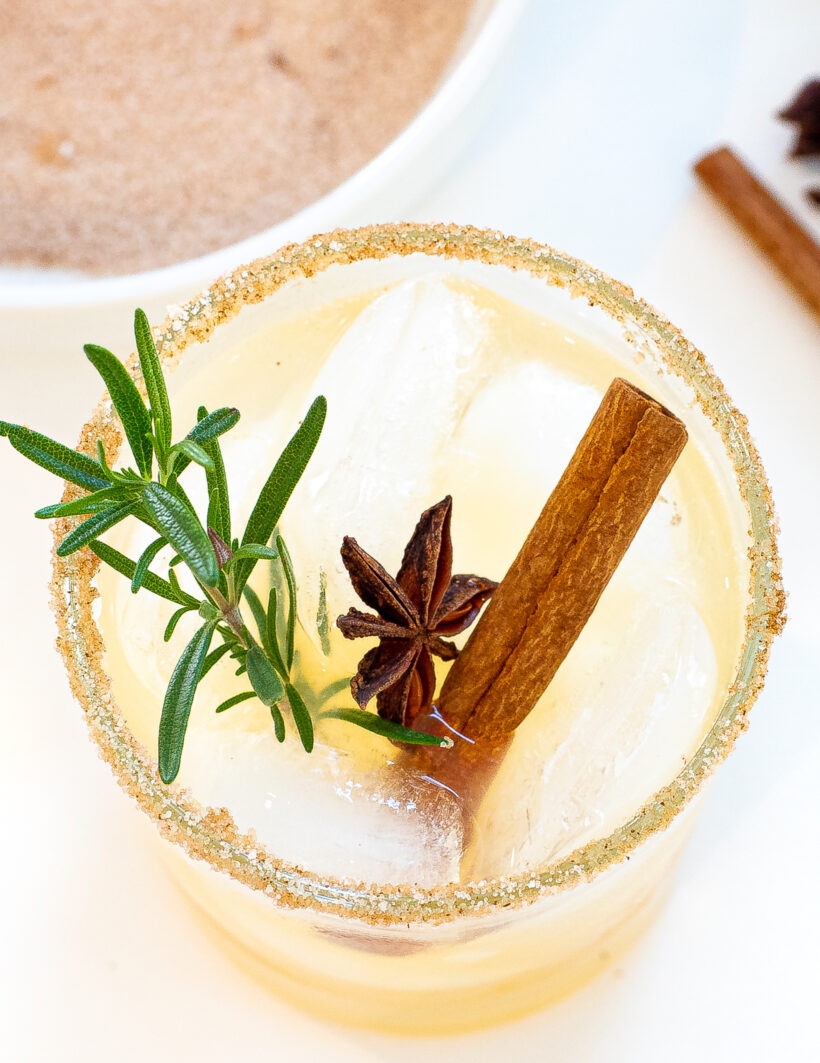 Overhead shot of apple cider margarita with rosemary, star anise and cinnamon as garnish.