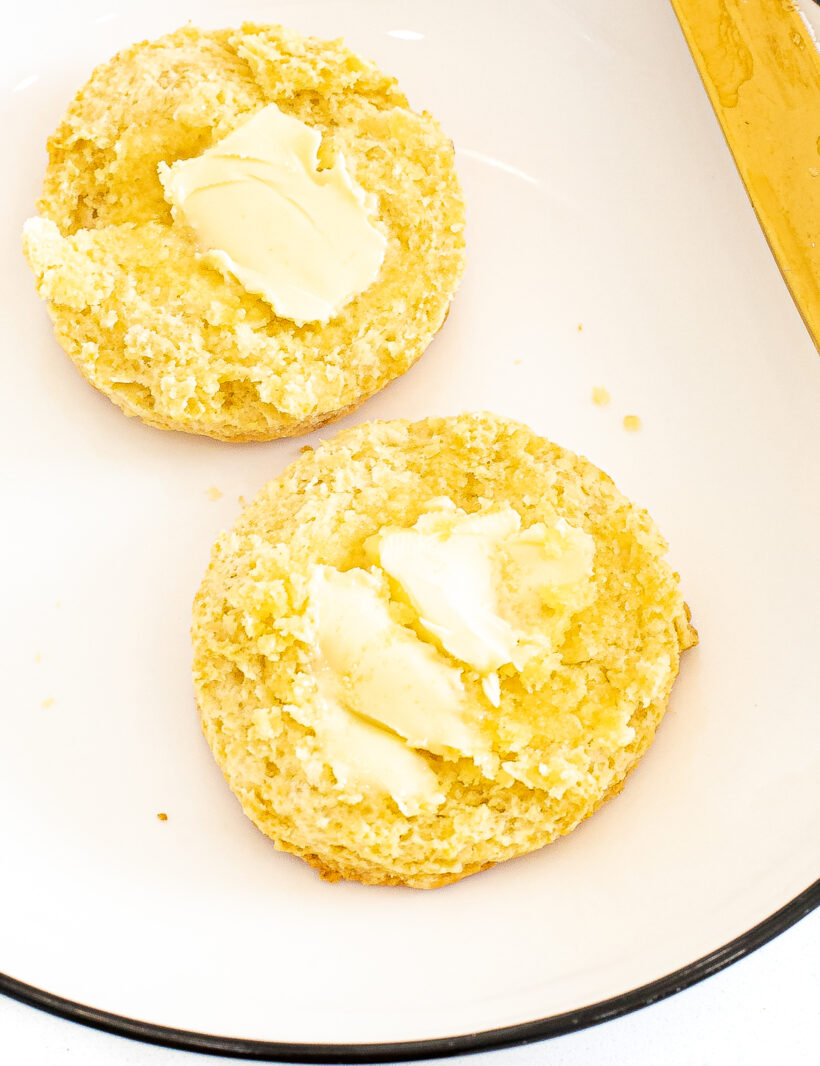 A buttermilk biscuit sliced in half and smeared with butter.