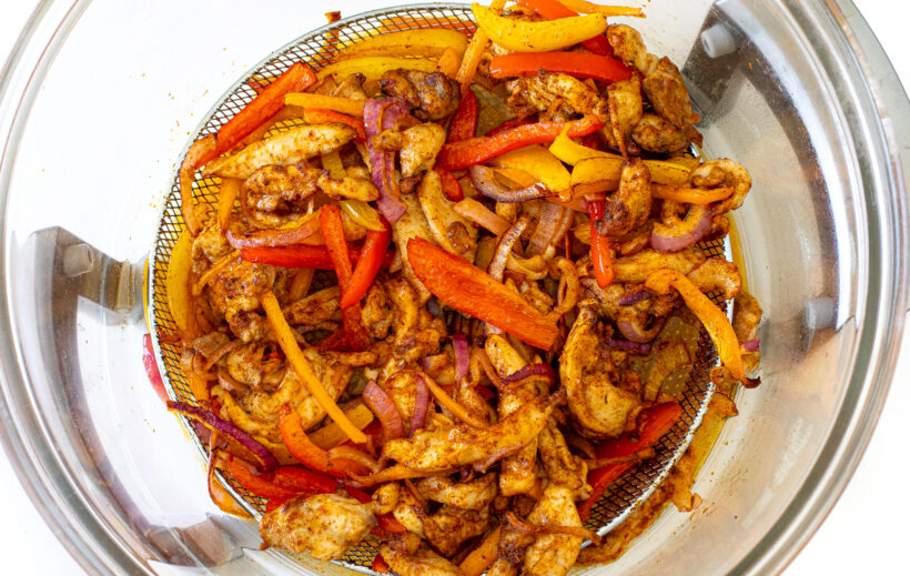 Cooked fajita ingredients in air fryer basket.