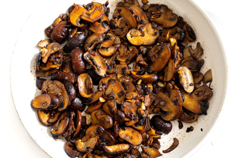 Sliced mushrooms cooking in a skillet. 