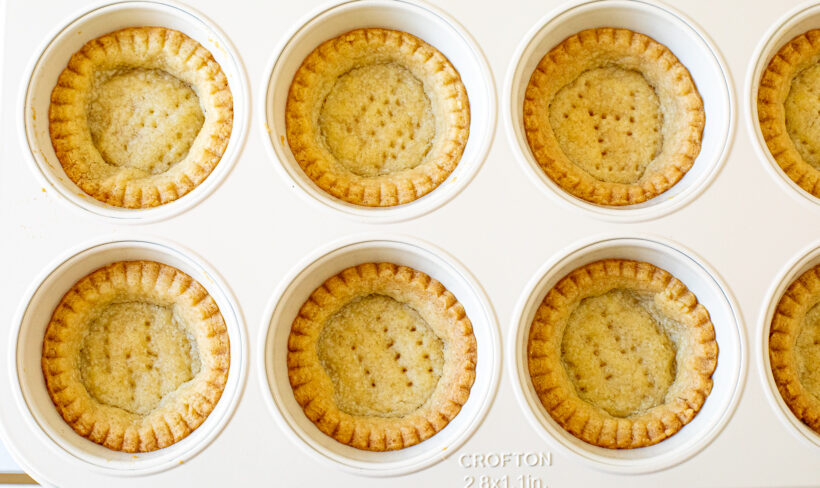 Baked tart dough in a muffin tin.