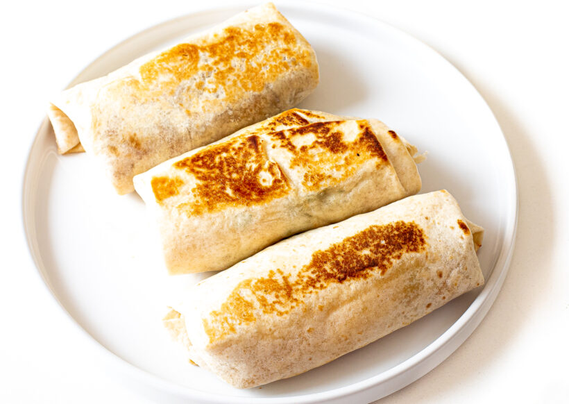 Seared breakfast burritos on a white plate.