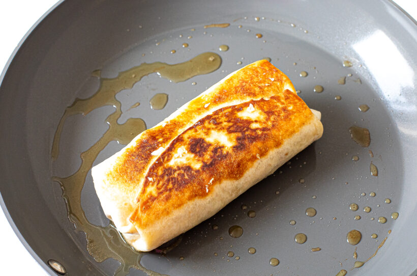 Seared breakfast burrito in skillet.
