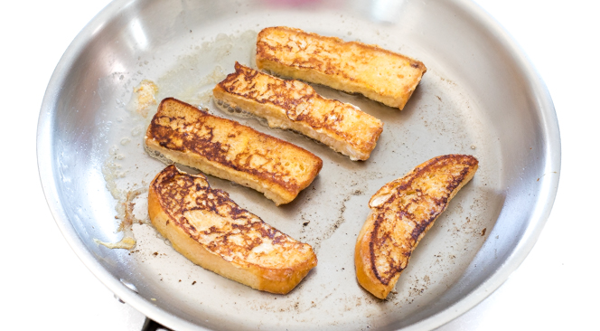 Frying the french toast sticks recipe in a stainless steel pan.