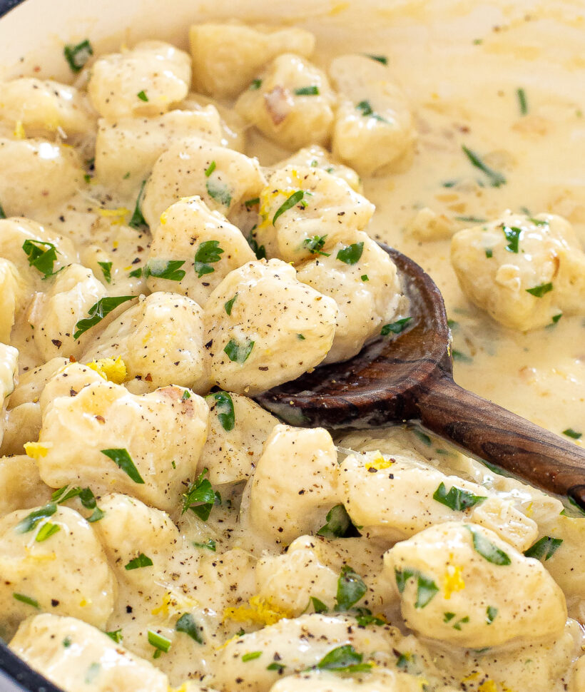Lemon parmesan gnocchi in a pan with a wooden spoon. 
