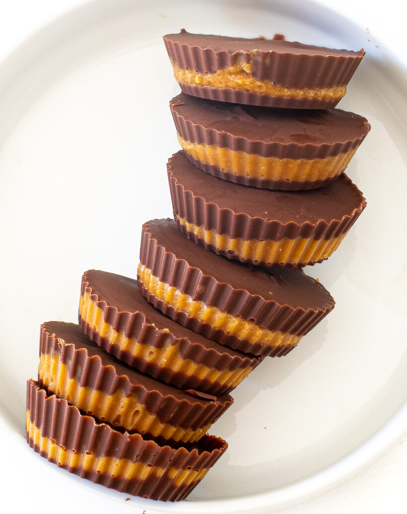 Peanut butter cups laying next to each other in a line on a plate.