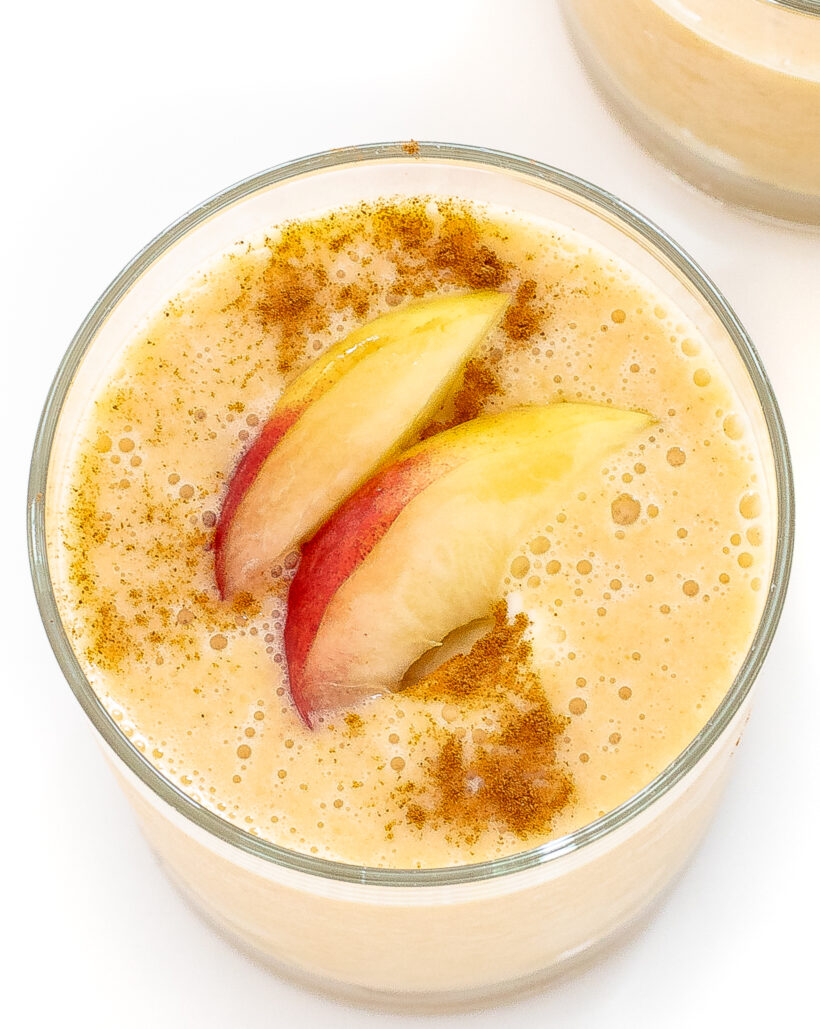 Overhead shot of peach smoothie with peaches and cinnamon on top.