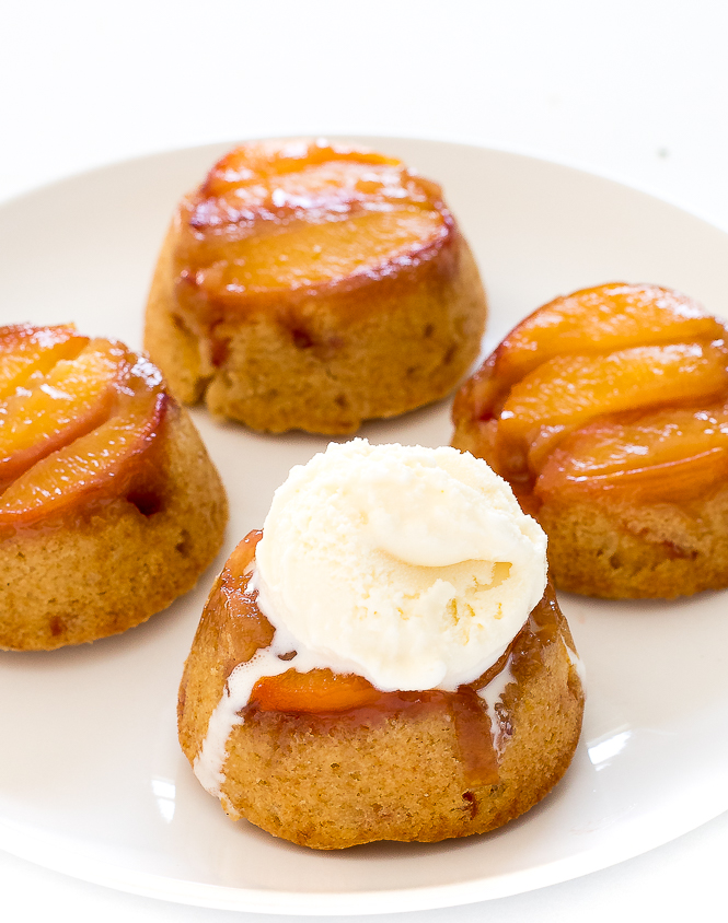 Mini Peach Upside Down Cakes on a white plate with a scoop of ice cream.