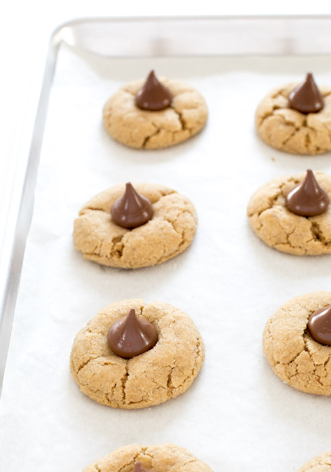 peanut butter blossom cookies with Hershey Kisses on top spread on a baking sheet