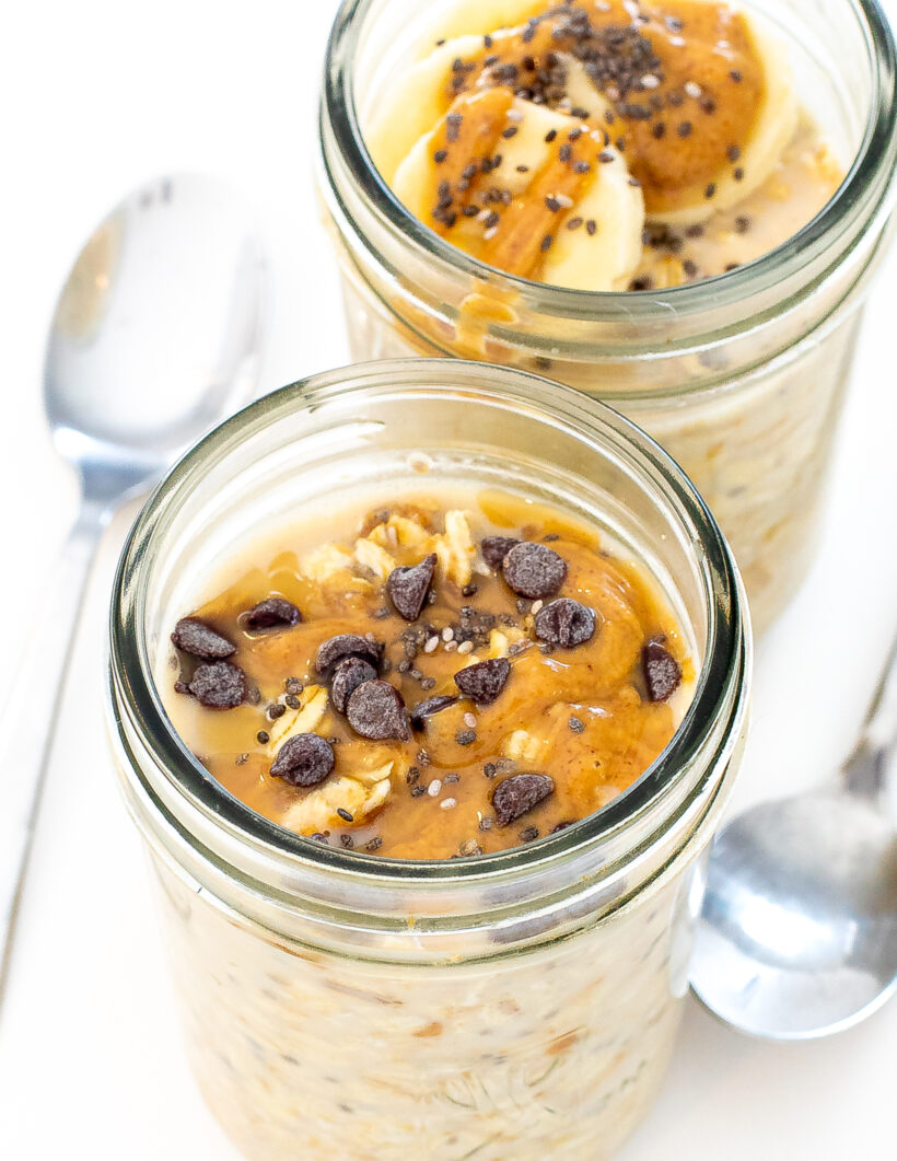 Two glass jars of peanut butter oats topped with chocolate chips.