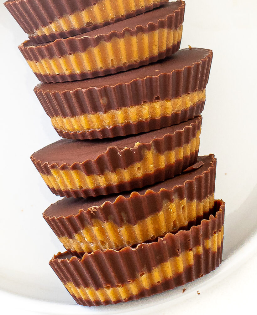 Homemade peanut butter cups stacked on top of each other on a white plate.