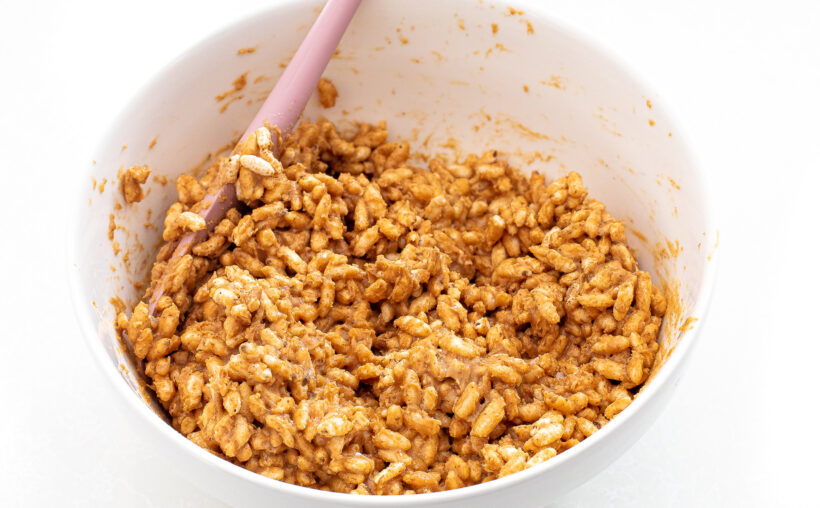 Rice crisps with peanut butter and honey in a mixing bowl. 
