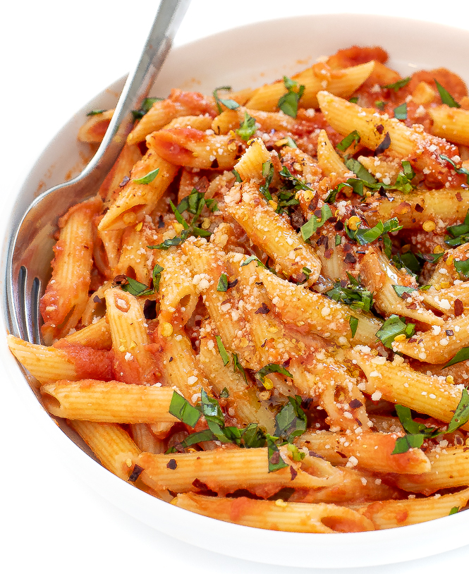pasta with vodka sauce in a white bowl sprinkled with fresh basil