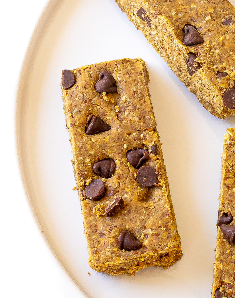 Close up shot of a protein bar with chocolate chips on top served on a plate. 