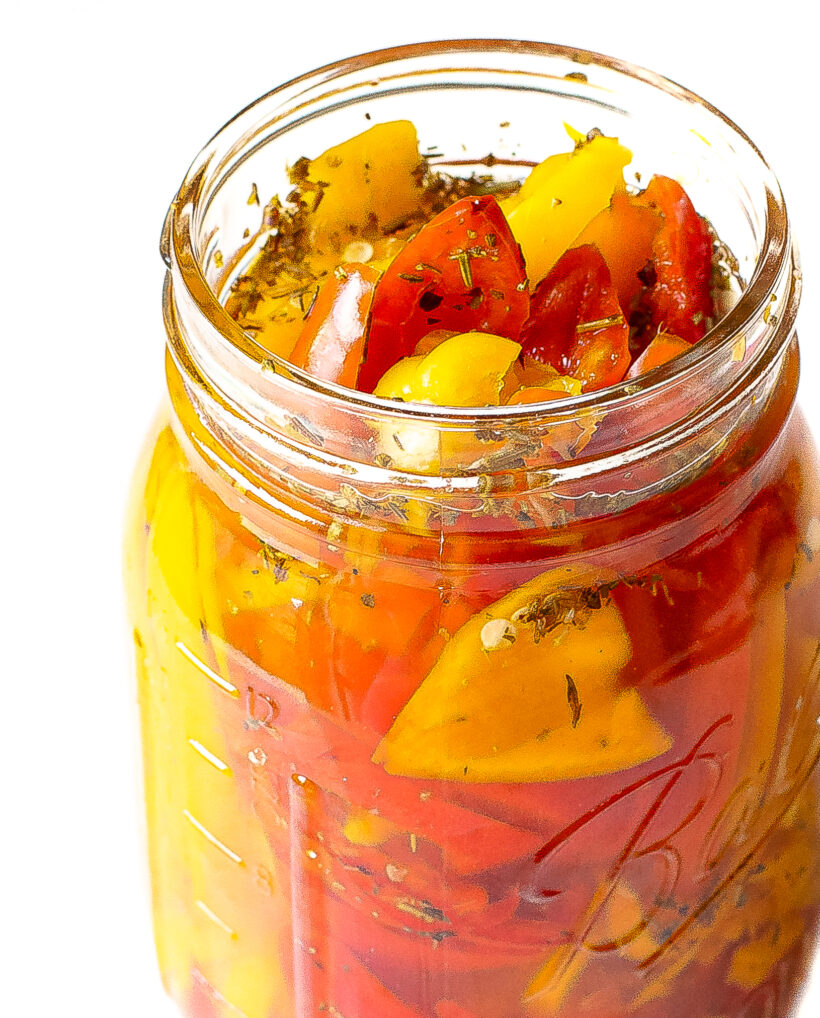Pickled bell peppers in a jar with the lid removed.
