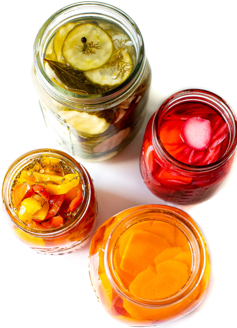 Four mason jars with various pickled vegetables.