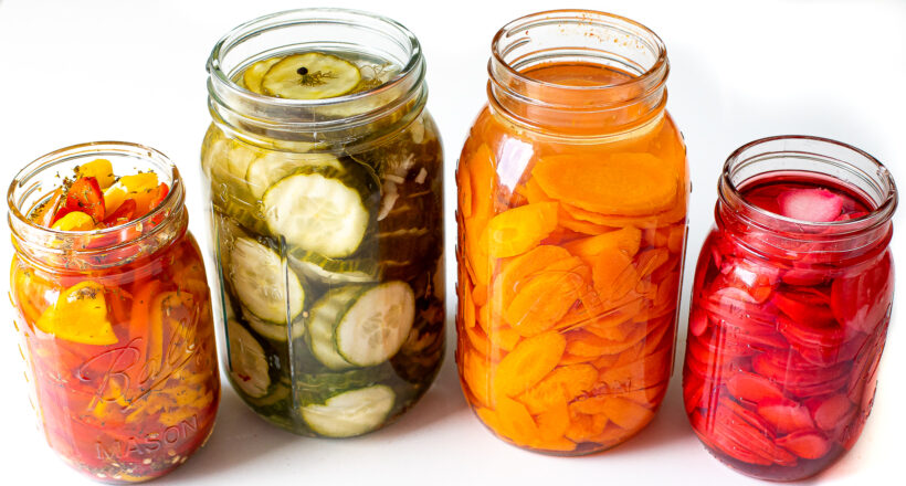 Sliced vegetables in brine in mason jars.