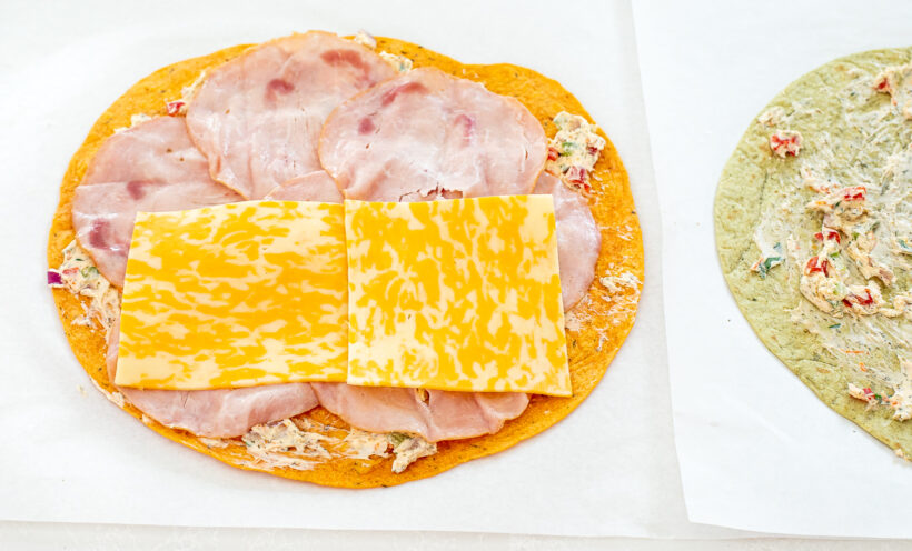 Ham and cheese being layer on top of the tortilla.